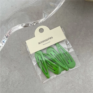 Lot de cinq barrettes BB vert herbe sur un emballage cartonné beige minimaliste