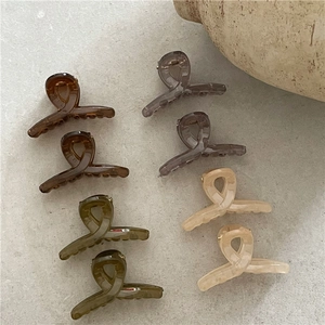 Jelly colored knot style hair clips in amber, grey-purple, and olive on marble