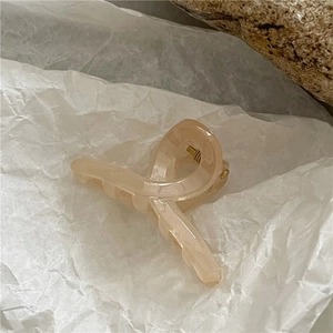 Detail of a minimalist translucent cream hair claw clip with a sleek crisscross design