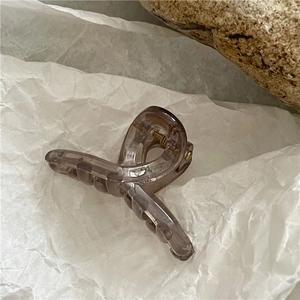 Detailed close-up of amber jelly hair claw clip with golden metal spring mechanism