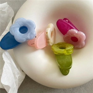 Detailed macro view of colorful marble textured acetate flower hair clips in a white ceramic tray