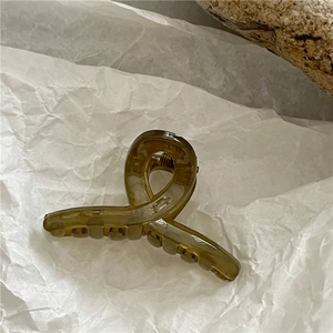 Detailed macro view of an amber translucent hair claw clip with cross-twist design