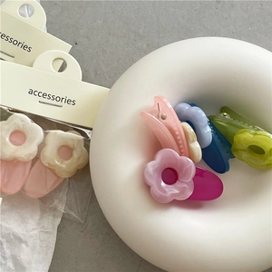Detailed close-up of colorful acetate flower hair clips with marble texture on white plate