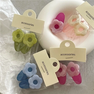 Detail of colorful acrylic flower hair clips in green and pink on a white background
