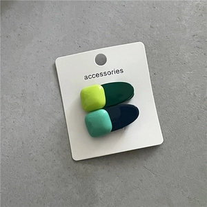 Détail macro de barrettes géométriques aux motifs contrastés jaune, vert et bleu moderne