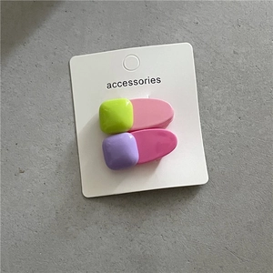 Détail de barrettes à cheveux en résine vert fluo et violet sur carte support