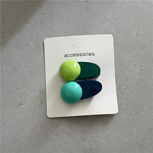 Détail de barrettes à cheveux géométriques en résine bleue et verte sur carte support