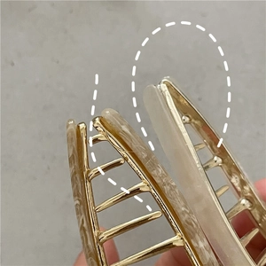 Detail of a 14cm large metal hair claw clip showing alloy teeth and acetate marble inlay
