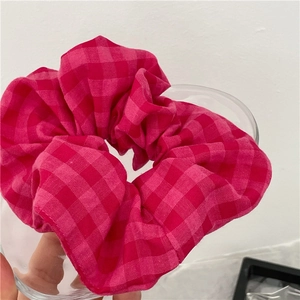 Chouchou à carreaux vichy rose sur un verre avec une texture de tissu doux
