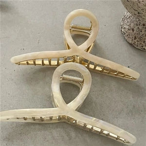 Detail of elegant cream marble acetate hair claw clip with golden metal spring mechanism