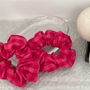 Détail d'un chouchou à carreaux roses sur un plateau en verre avec texture textile
