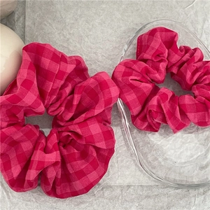 Chouchous en tissu à carreaux roses et rouges sur fond texturé avec décor en verre
