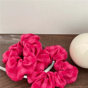 Détail de chouchous en tissu vichy rose avec plis texturés sur une plaque de verre