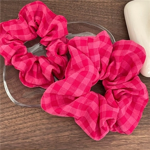 Détails de chouchous en tissu à carreaux roses présentés sur un plateau en verre élégant