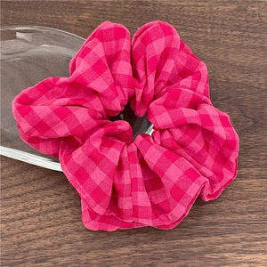 Détail d'un chouchou à carreaux rouge et rose montrant la texture du tissu