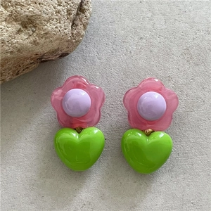 Dettaglio di orecchini a fiore rosa con perle viola e cuori verdi in resina lucida