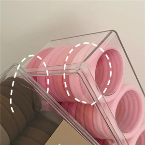 Dettaglio di elastici per capelli senza cuciture rosa e terra in scatola di acrilico