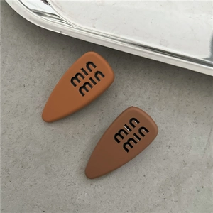 Close-up of matte rubber finish hair clips in orange and brown with min min text