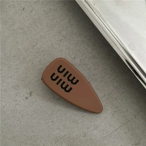 Detailed view of matte brown hair clip with black min min letters and resin finish