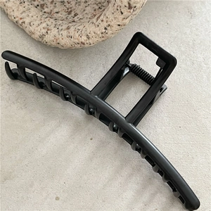Detail of matte black hair claw clip showing strong metal spring and teeth texture