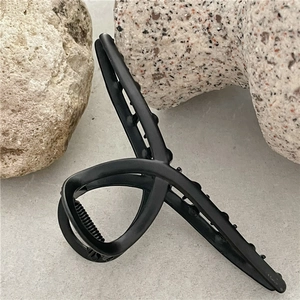Detail view of a matte black claw clip with a twisted geometric design and non-slip teeth