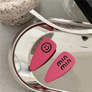 Close-up of matte rose pink hair clips with green smiley face and min min text