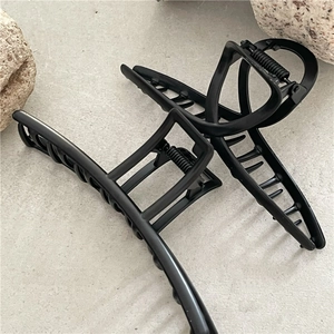 Minimalist matte black alloy hair claws in rectangular and cross styles on stone