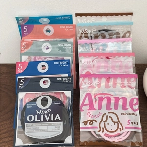 Detail of multi-color seamless hair ties in transparent packaging on a wooden table