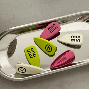 Macro view of matte finish alloy hair clips with smiley face and letter patterns