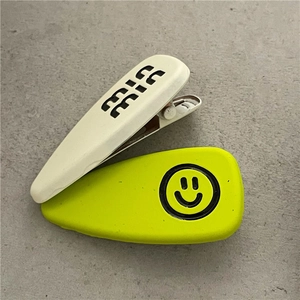 Detailed macro view of cream mia and neon green smiley face matte hair clips