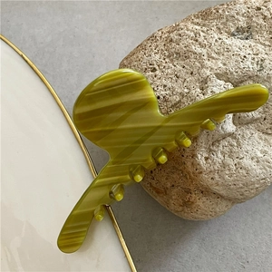 Detail showing olive green marble texture and teeth design of acetate hair claw clip