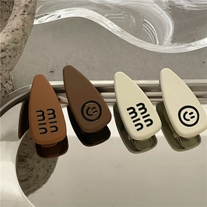 Detailed view of matte rubber finish hair clips with smile and letter prints on a tray
