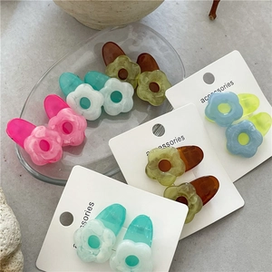Macro detail of jelly resin flower hair clips in various pastel colors on a marble base