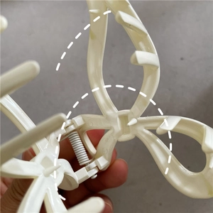 Détail d'une pince à cheveux crème en forme de nœud avec ressort métallique blanc