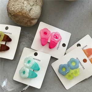 Detailed macro view of colorful translucent resin flower hair clips on a white display card