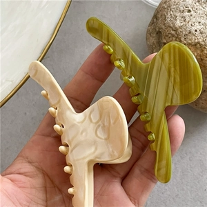 Detail showing olive green and cream marble acetate hair claws on a decorative tray