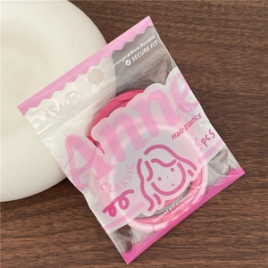 Macro detail of 5pcs pink elastic hair ties in a branded package on a wooden desk