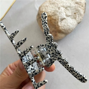Close-up of acetic acid hair claw clip with black and white spotted dalmatian pattern