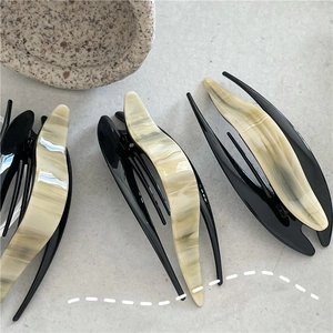 Detail view of marble pattern acetate hair clips with sleek black resin base design