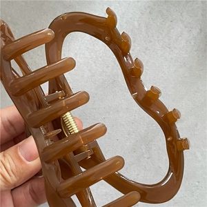 Détail d'une pince à cheveux ambre avec ressort doré et finition en résine polie