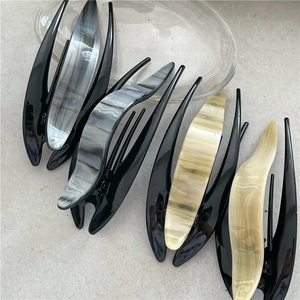 Close-up of marble pattern acetate hair claws in four colors on a glass tray