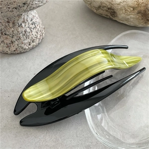 Detailed view of elegant black acetate hair clip with marble pattern on a stone base