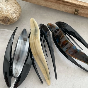 Detail of four acetate hair clips with marble and ink patterns on a natural stone base