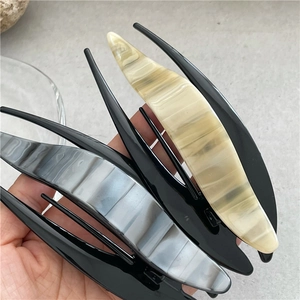 Close-up of marble texture acetate hair claws in beige and grey with glossy black teeth