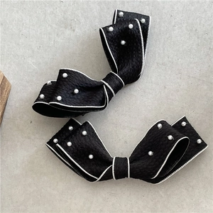 Set of two black bow hair clips with white edge stitching and delicate faux pearls