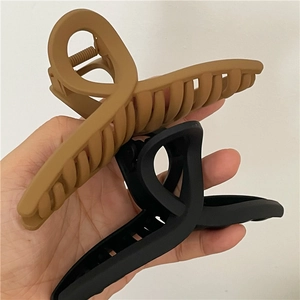 Détail de grandes pinces à cheveux croisées noir mat et marron caramel pour femmes