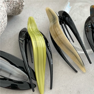 Macro detail of tortoiseshell and marble acetate hair clips on a minimalist stone surface