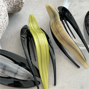 Close-up of minimalist acetate hair clips with marble texture on a stone surface