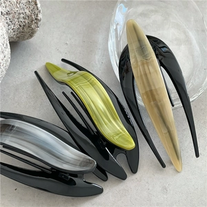 Three acetate marble hair clips in grey, green, and beige on a grey stone surface