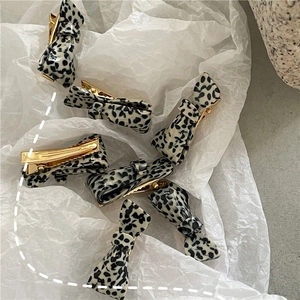 Detailed close-up of dalmatian print acetate bow hair clips on white paper background